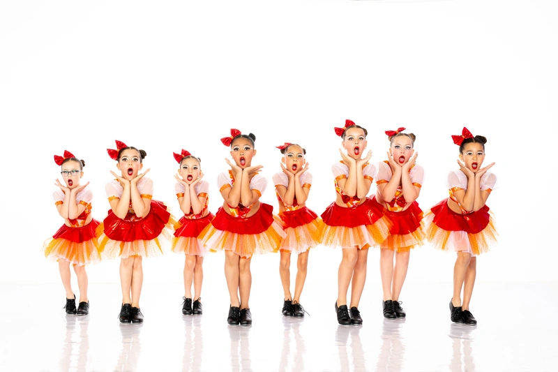 Young kids jazz dance class in red and orange costumes performing at a Barrie dance studio